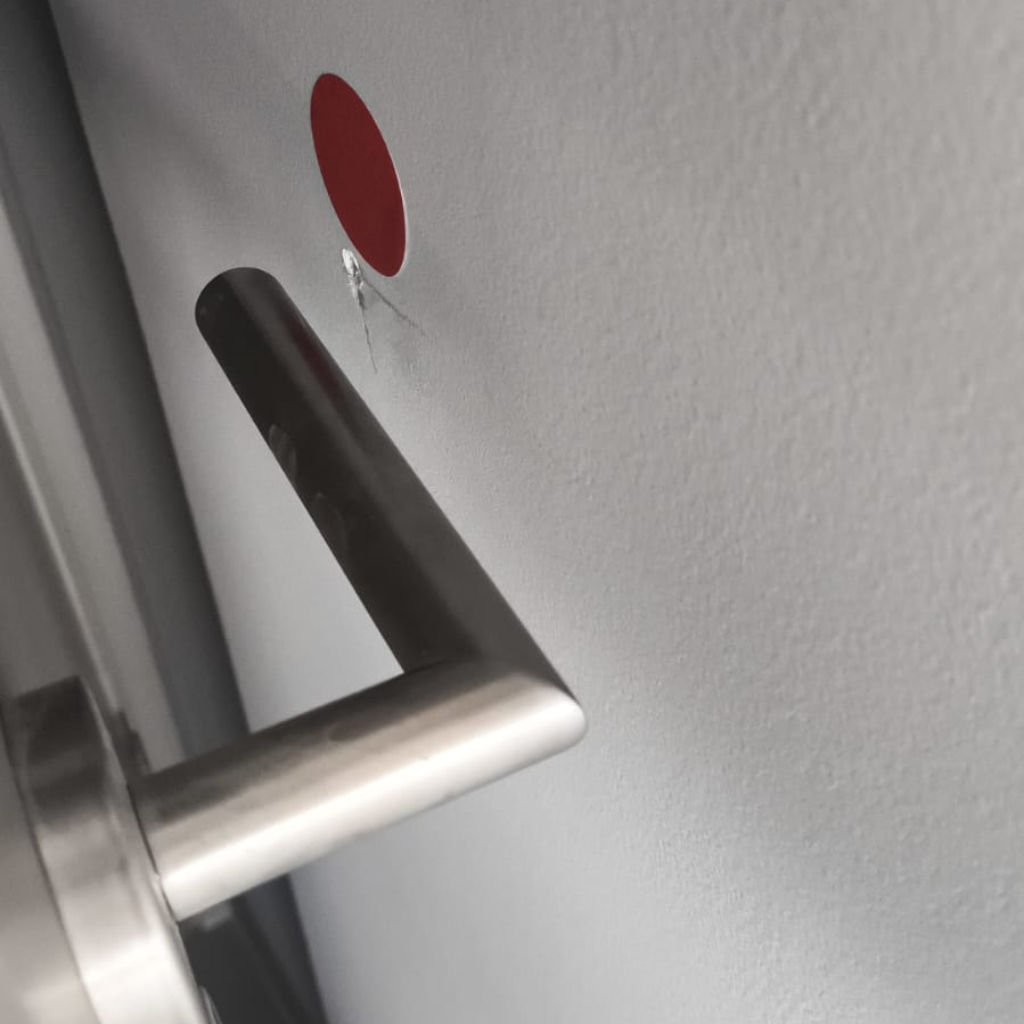Laudo de vistoria de imóvel novo apontando defeito de acabamento com pintura lascada em parede e guarnição de porta.